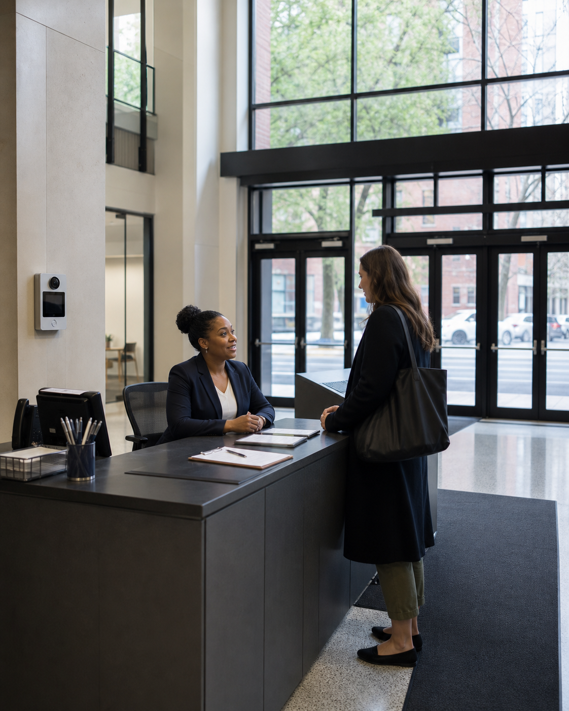 Staff member assisting a visitor at a secure school lobby check-in desk in Manhattan.